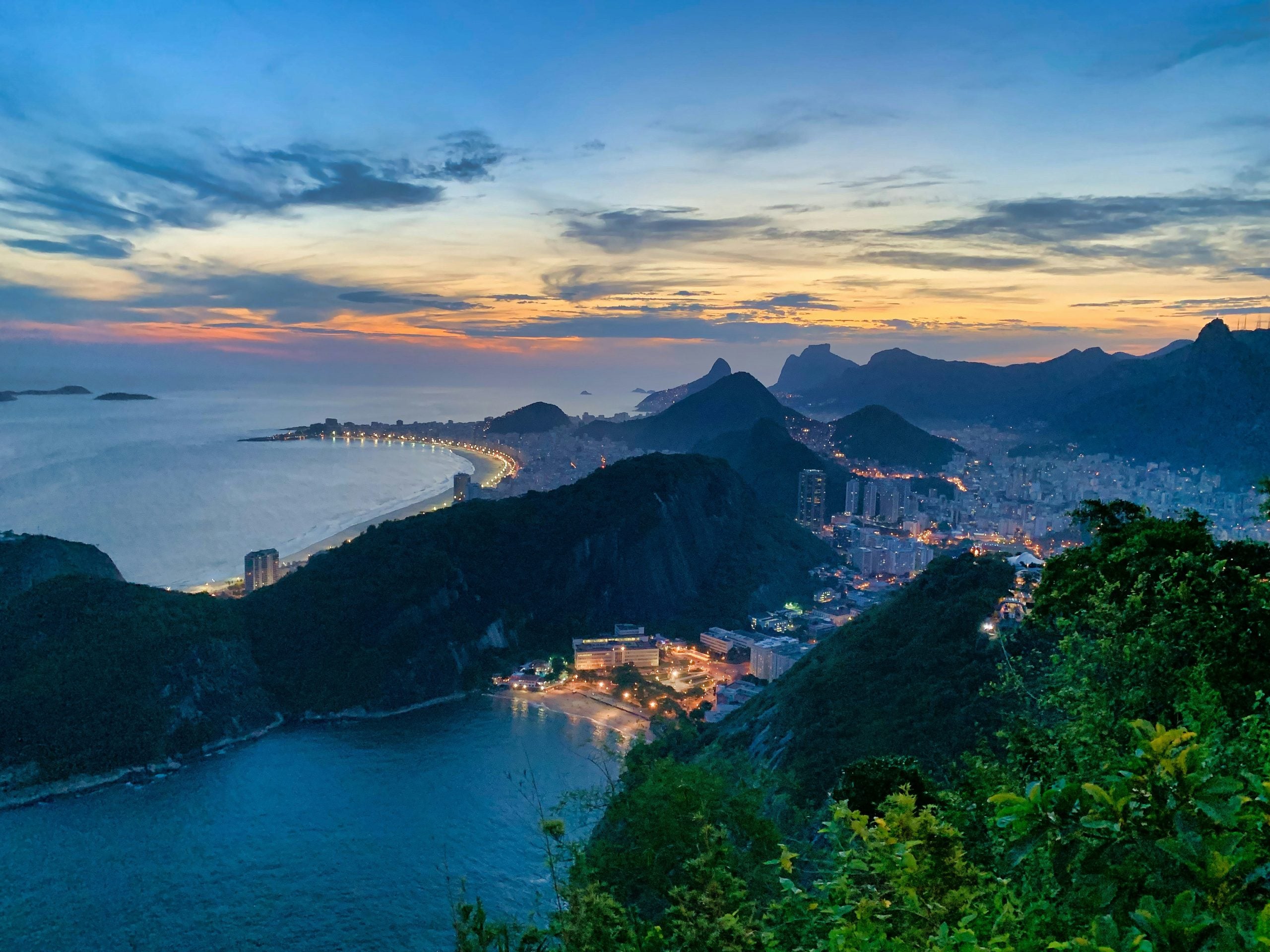 Panoramic view of Rio de Janeiro at dusk with mountains, coastline and city lights