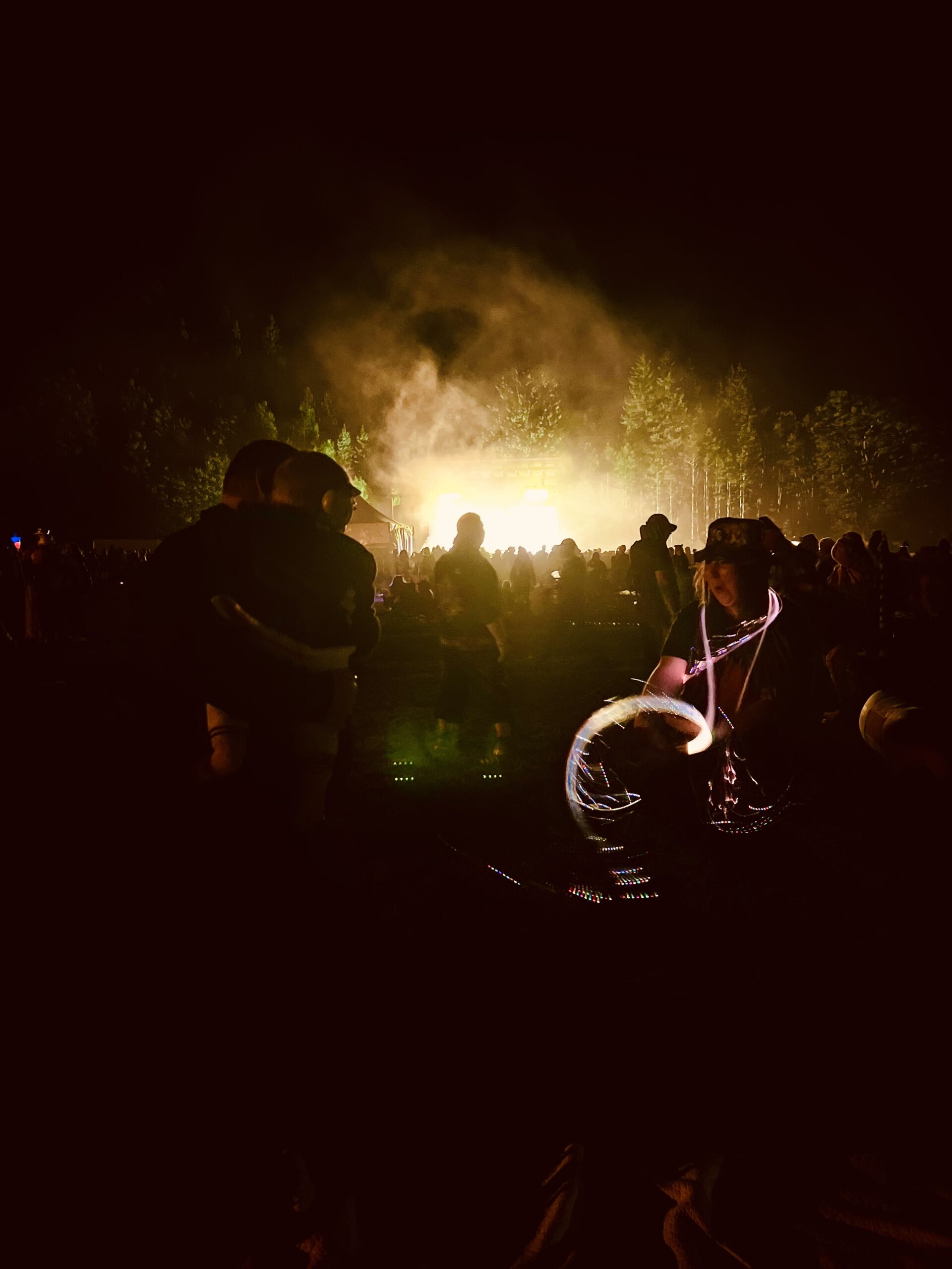 Parent holding a baby wearing protective earmuffs during a nighttime performance at Camp Alderwild in Telluride