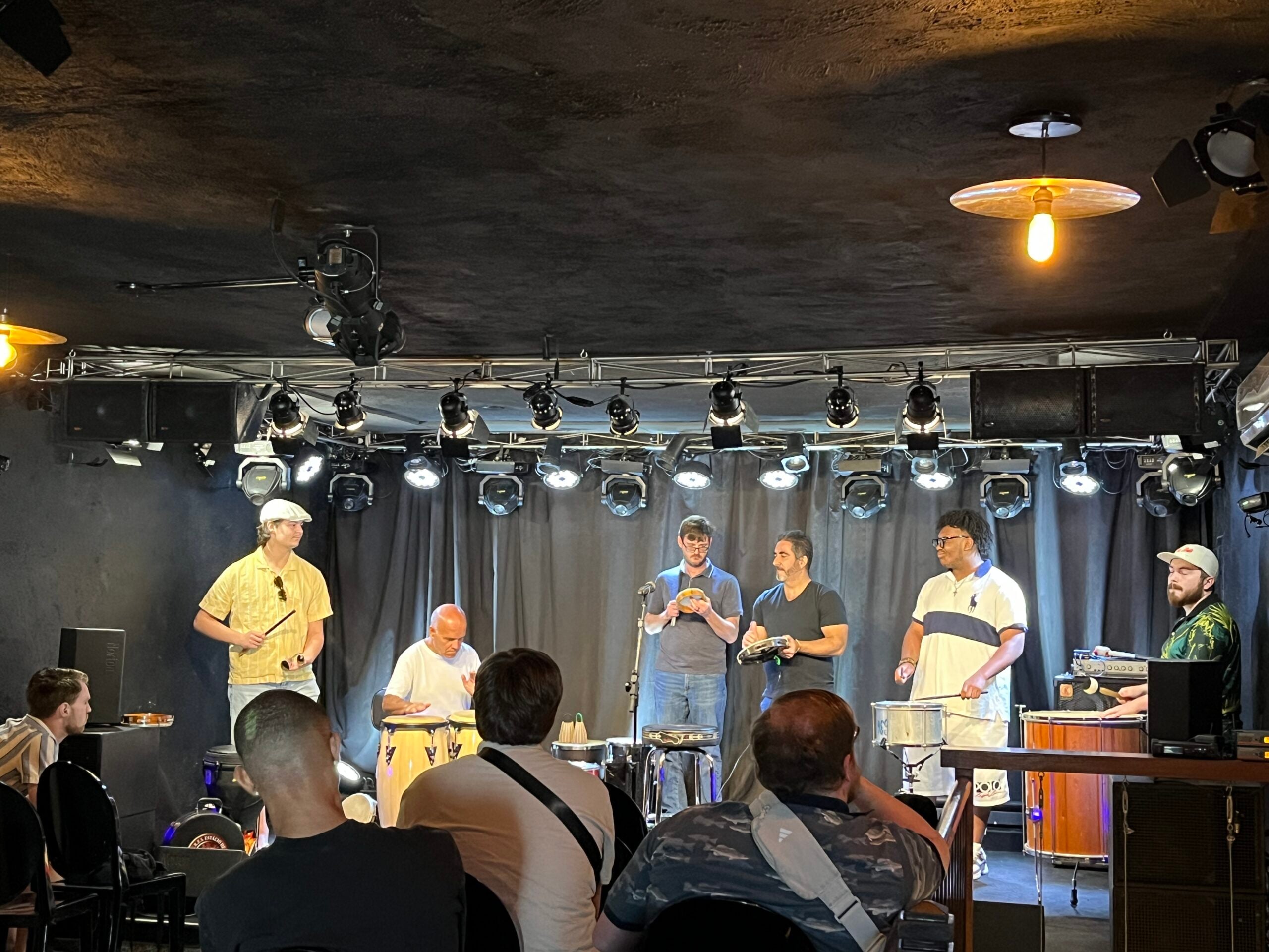 Students and local musicians learning Brazilian percussion together during an educational music workshop in Rio de Janeiro