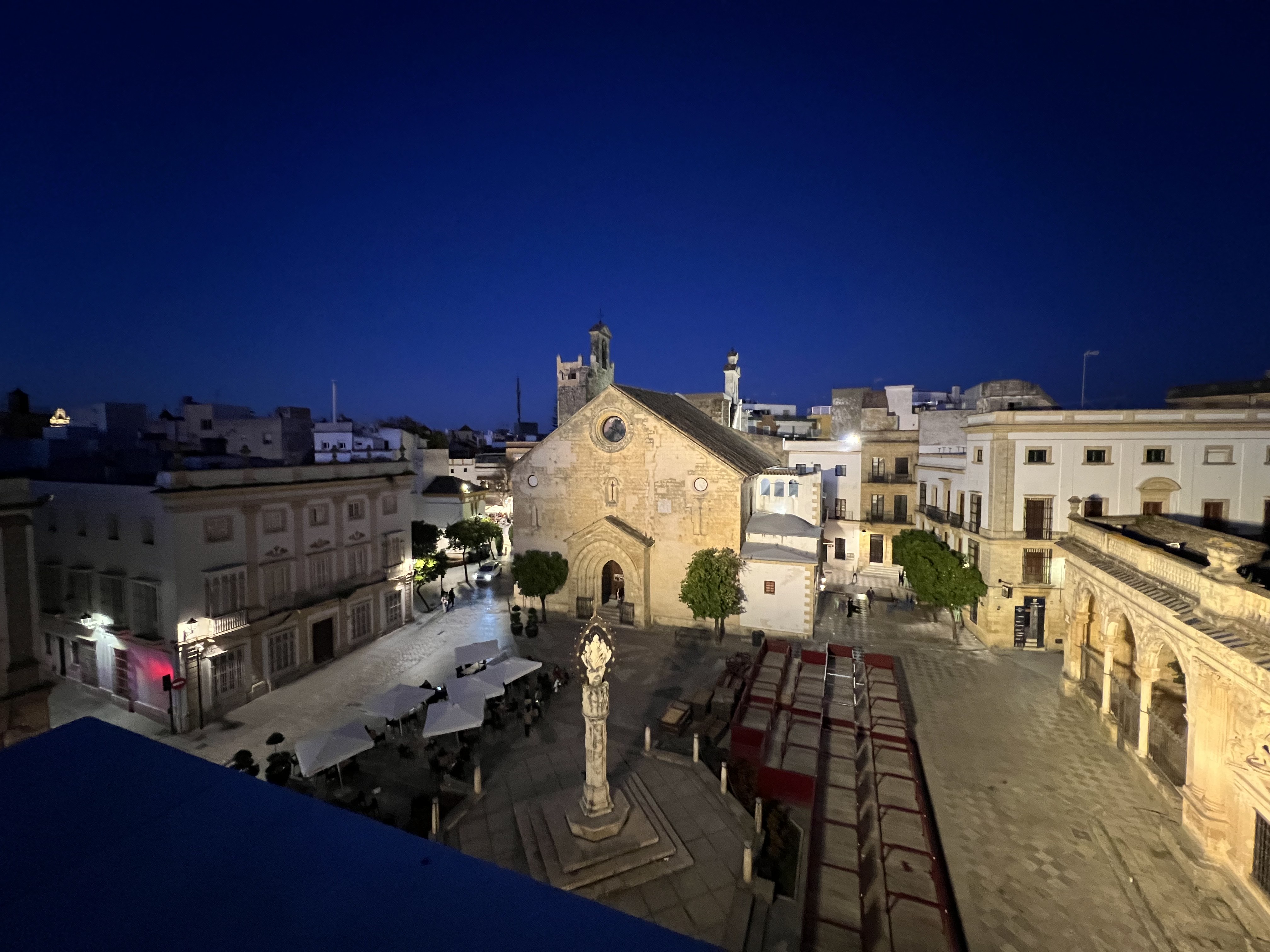 An illuminated church and historic square in Jerez at dusk, photographed from above.