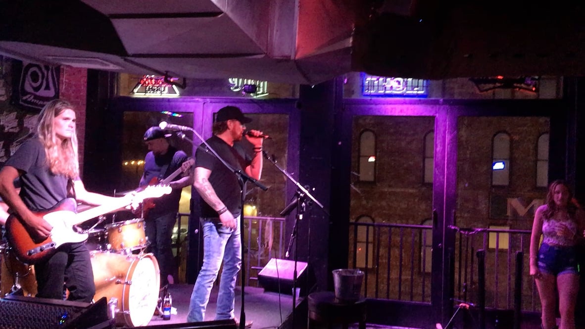 Musicians performing with electric guitar and drums in a Nashville venue