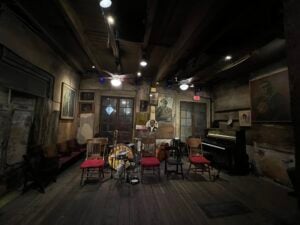 An intimate New Orleans music room with piano, double bass, drum kit and chairs