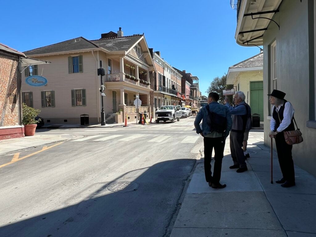 Travelers pausing on a New Orleans neighborhood walk beside historic houses